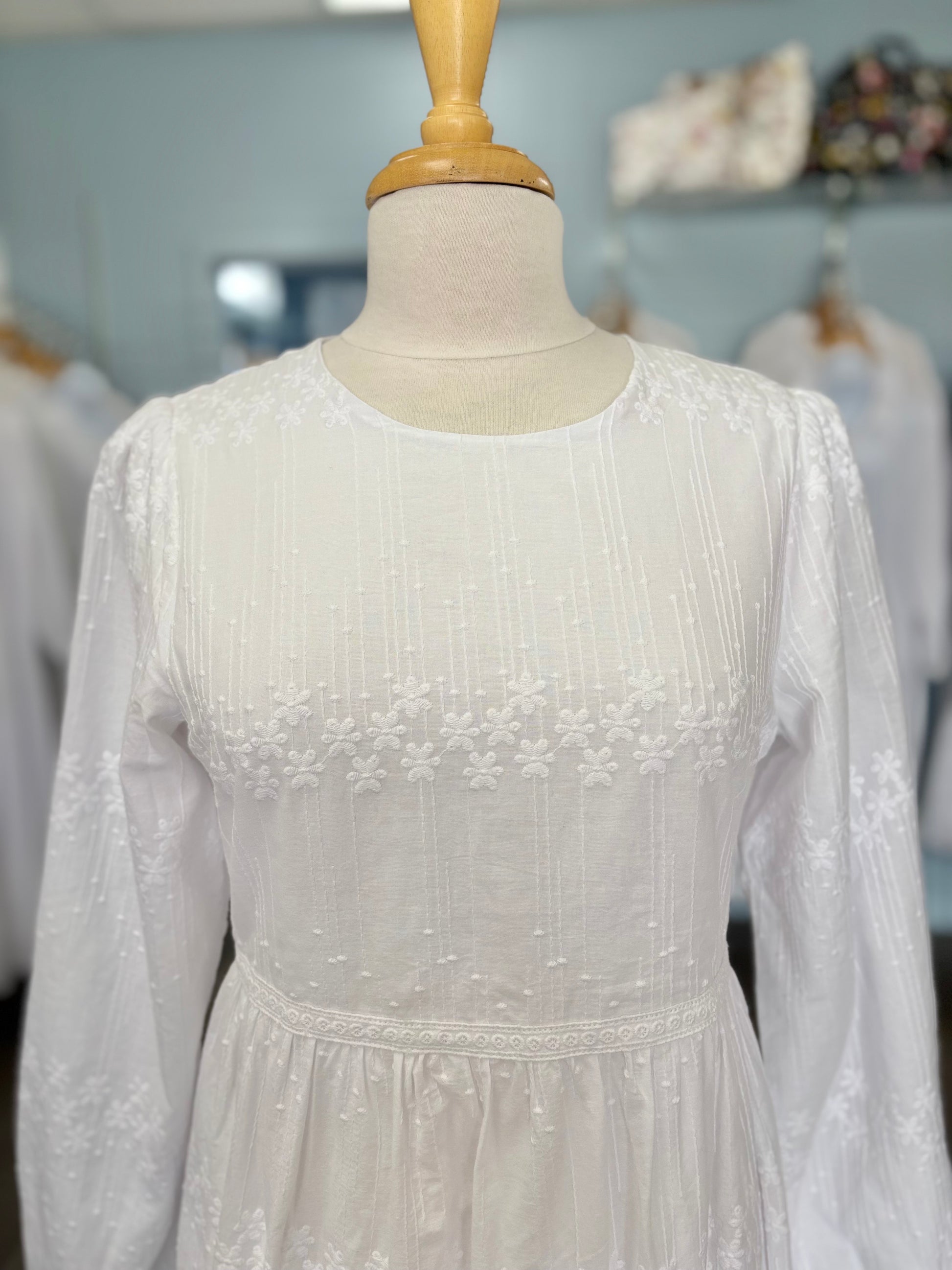 Close up of white dress with embroidery.