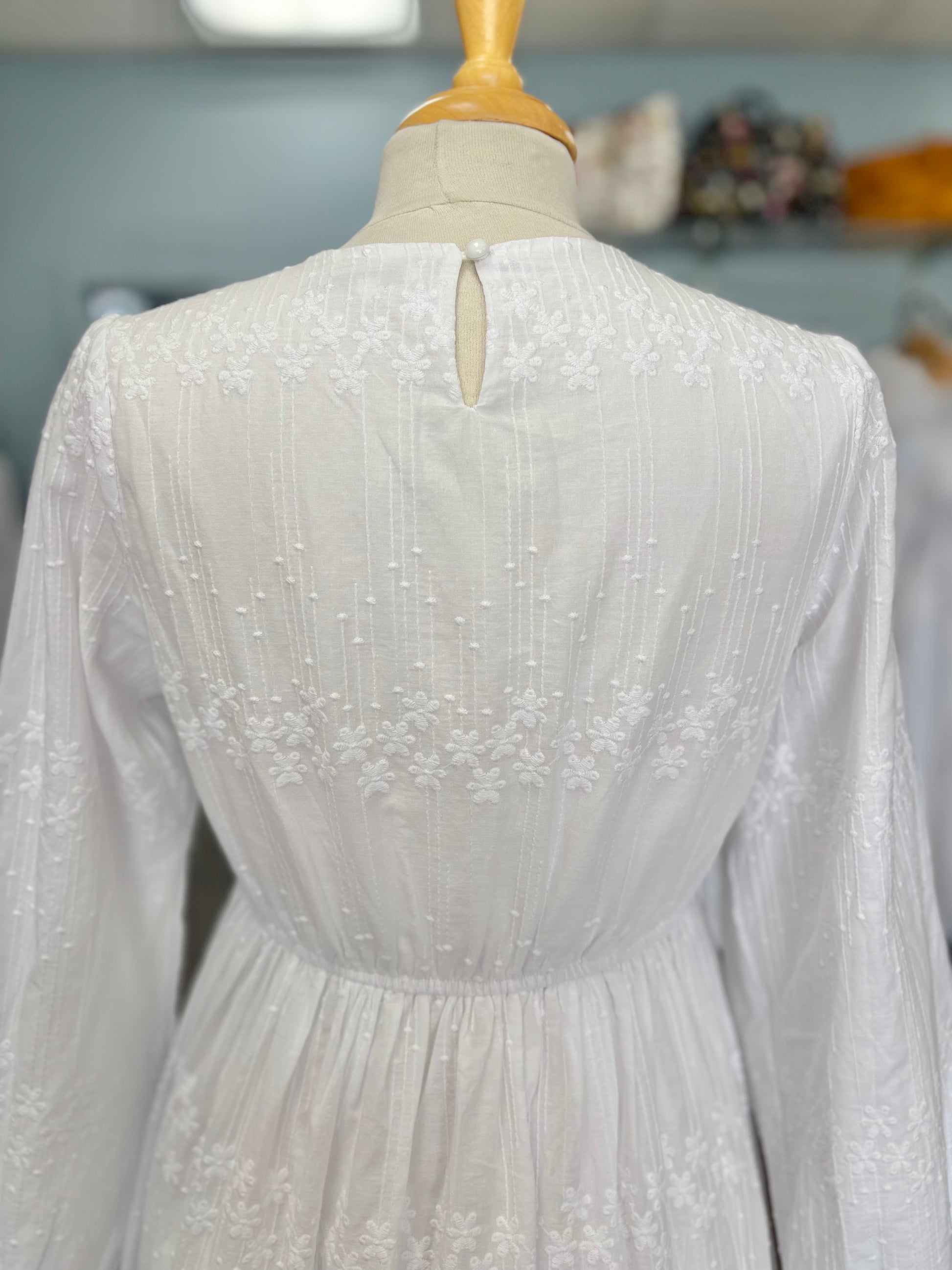 Close up of back button on long white dress. 