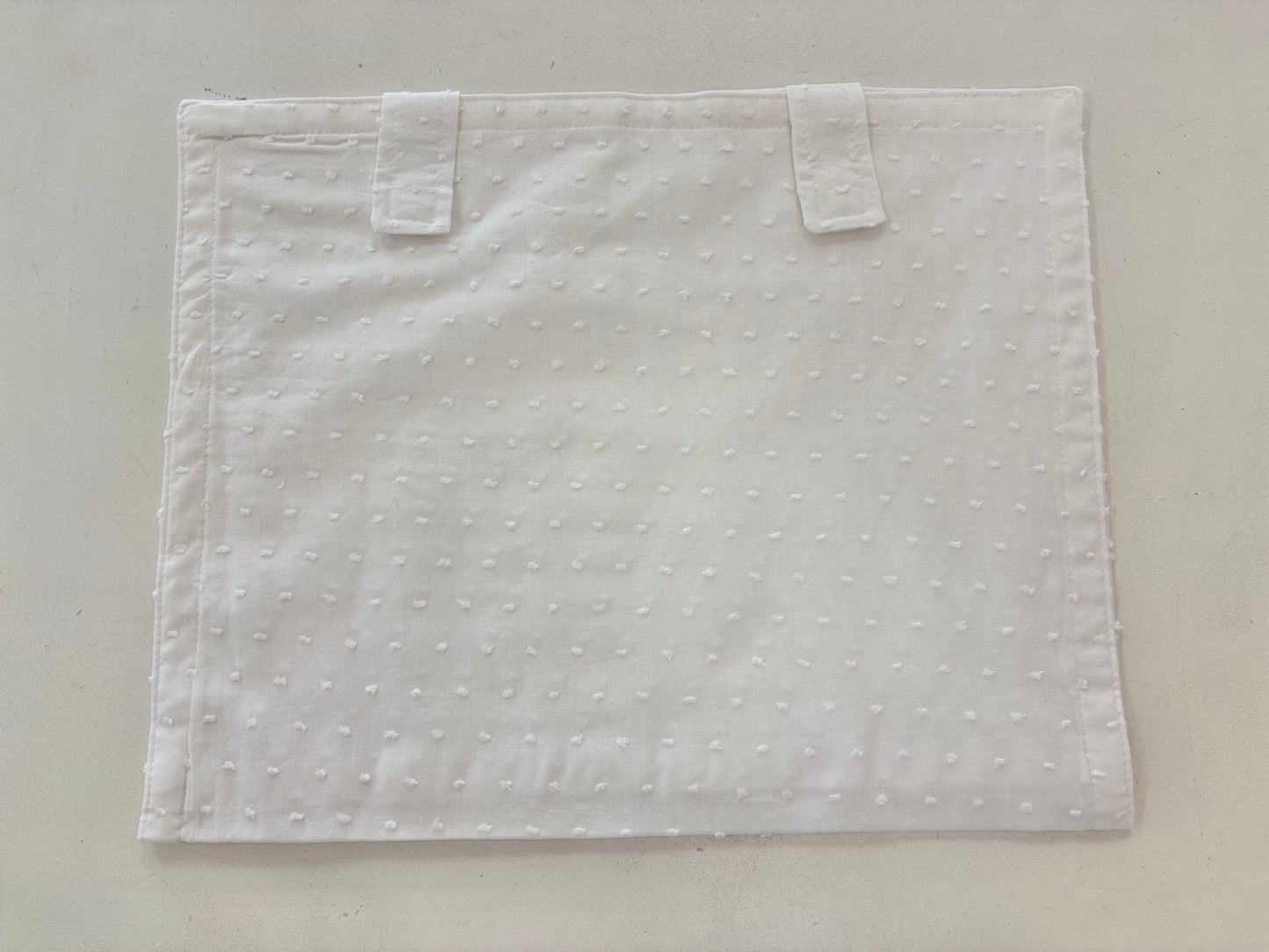 White cotton envelope with Velcro strap closure.