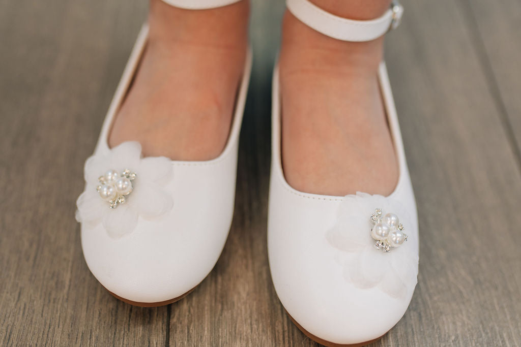 girl's white shoe with strap and flower on toe