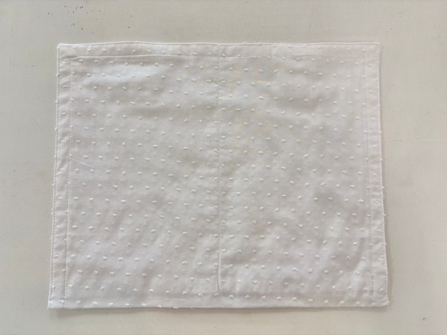 White cotton envelope with Velcro strap closure.